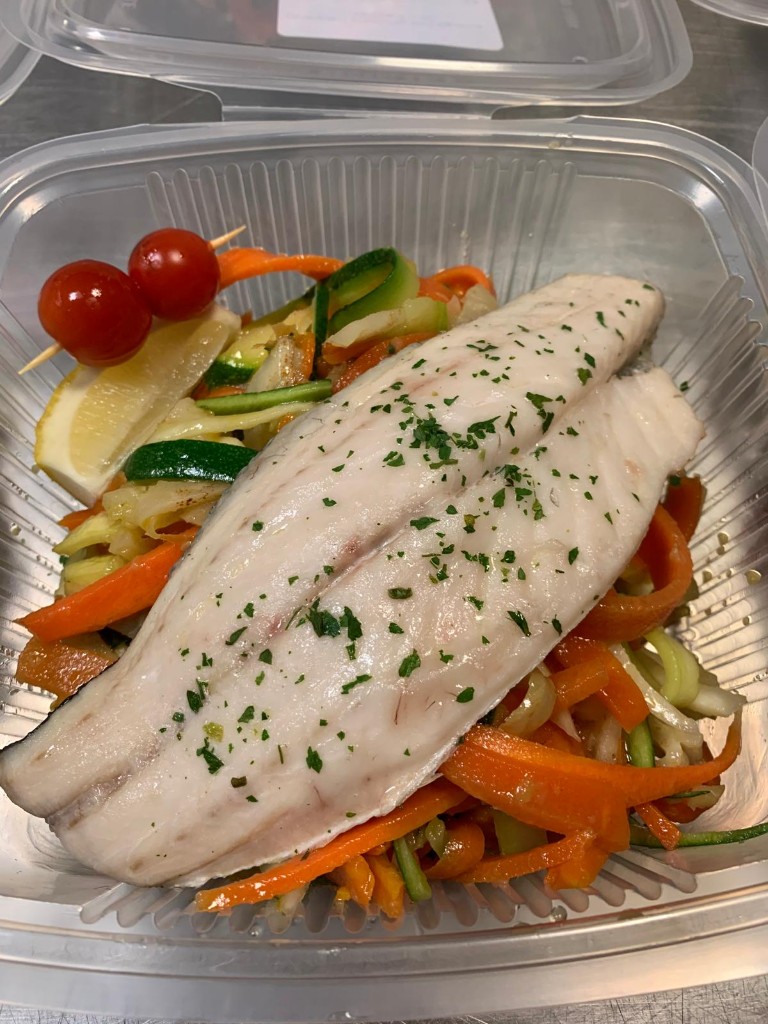 Filet de poisson blanc au persil sur une julienne de carottes et de courgettes, avec tomates cerises et quartier de citron