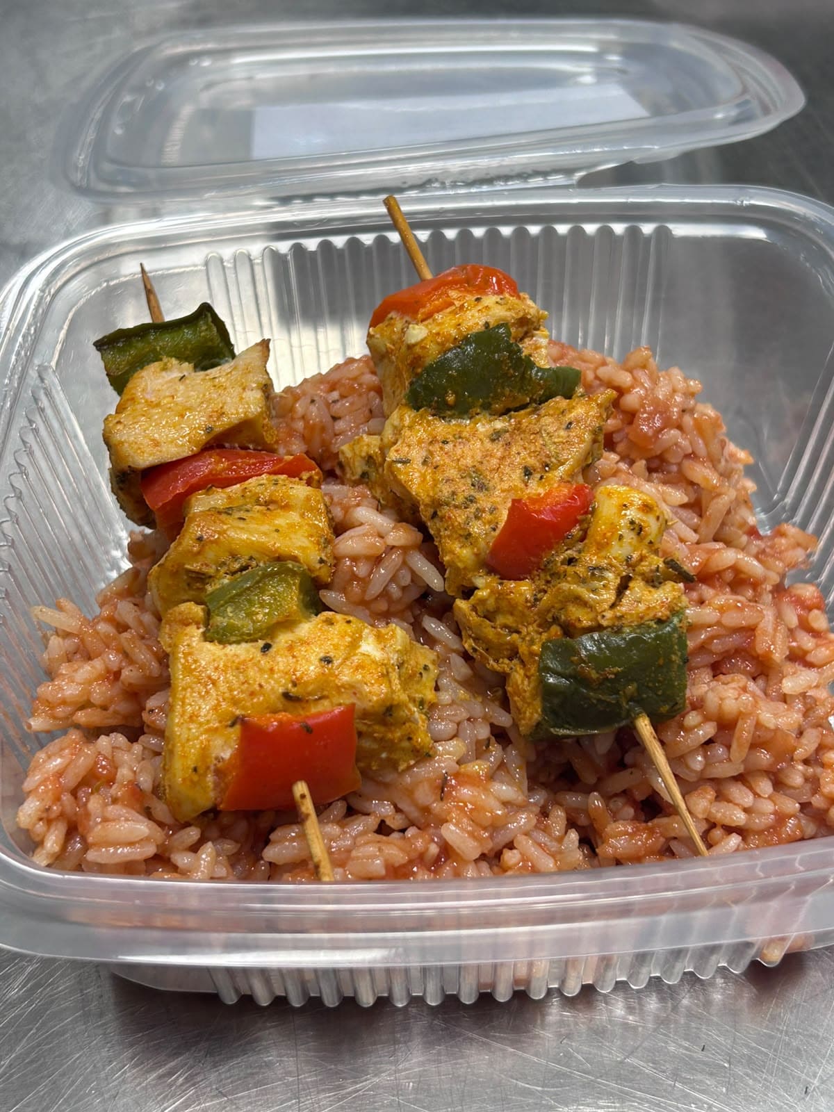 Brochettes de poulet aux poivrons, servies sur du riz rose dans une barquette Mazal 7